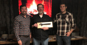 Two men stand next to the 2018 Wrench of the Year winner, Curtis Steckler.