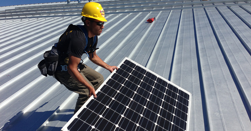 A man installing solar panels on a metal roof