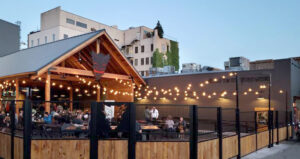 A patio of a brewery with string lights at dusk