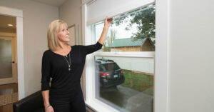 a woman smiling, closing her energy efficient windows