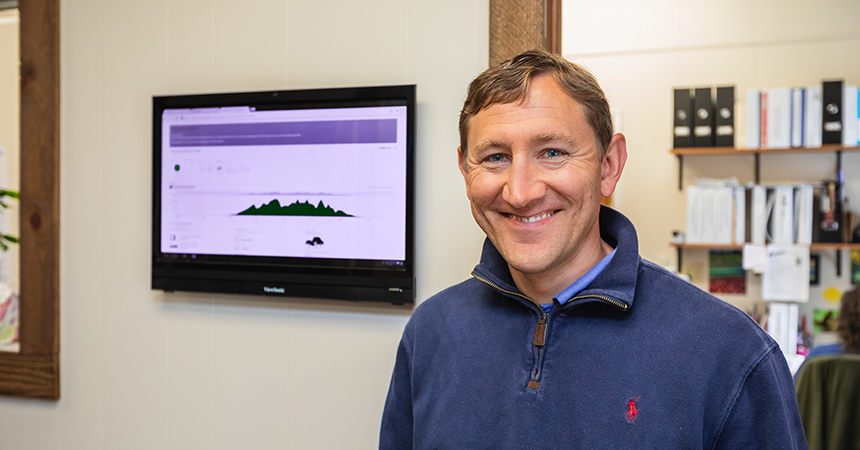 a man smiling in front of a display showing energy savings