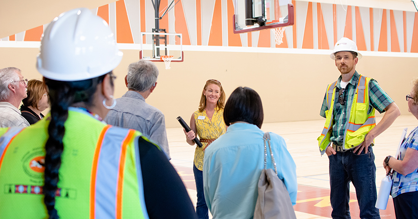 a man in a hard hat addressing a tour in a basketball court