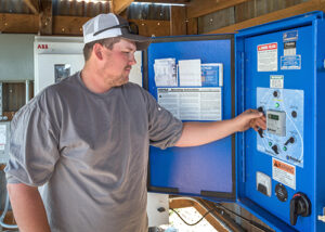 Man adjusting controls of his irrigation system and pumps.