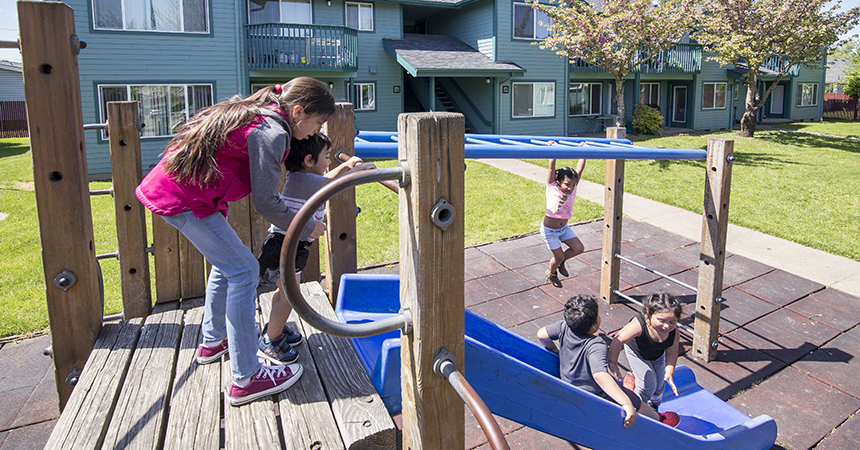 children playing on a play set outside of a green apartment building