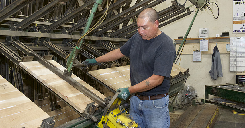 a person with a shaved head cutting lumber in a factory setting