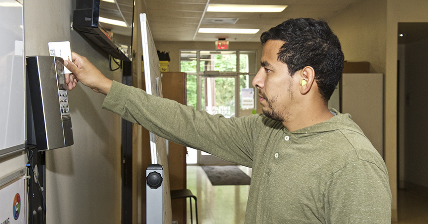 A person with short hair and a goatee swiping a card in a machine