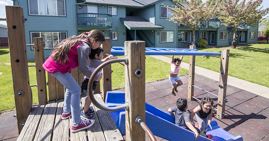 Children playing on a playground in front of an apartment building