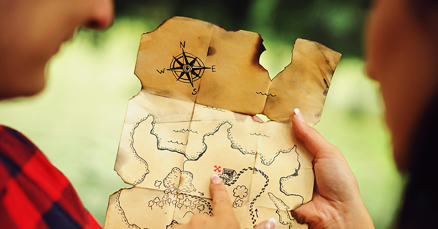 Couple of lovers holding a pirate map in hands and looking for treasures. Romantic quest journey concept. Love story