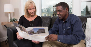 a man and woman looking at a pamphlet on a couch