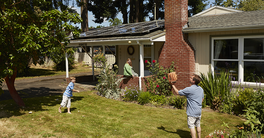 Family playing catch in front of house with solar panels
