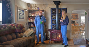 a man and woman in a cozy living room with a fireplace