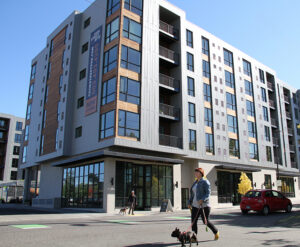 Person walking dog in front of apartment building