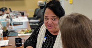 two women talking at a conference table.