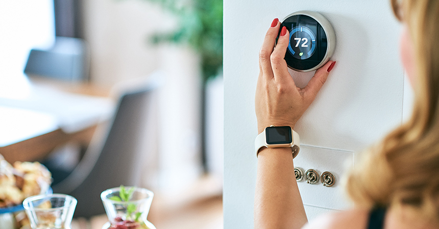a woman adjusting a smart thermostat