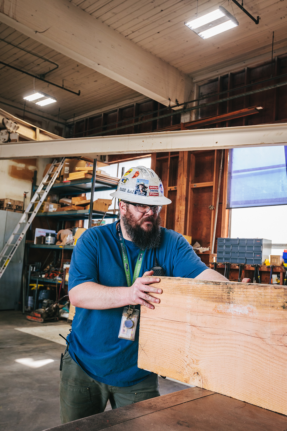 a bearded man in a hard hat moving lumber