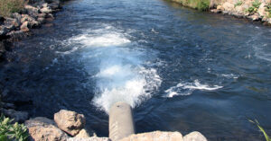water flowing out of an irrigation pipe into a channel