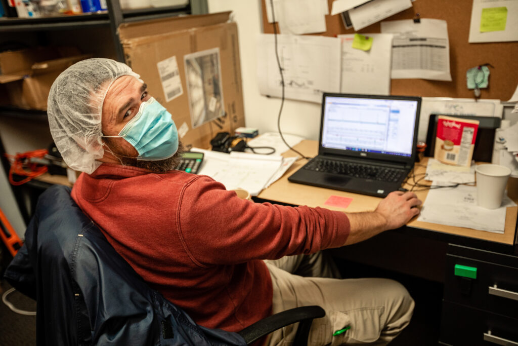 A person in a computer chair wearing a hair net and face mask