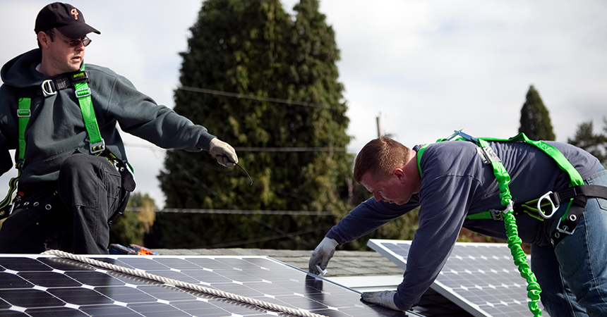 two people installing a solar panel on a roof