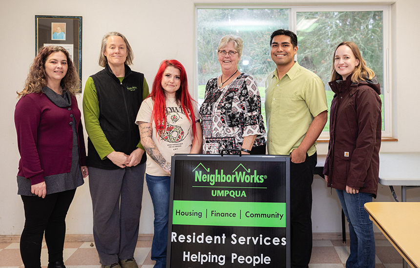 NeighborWorks Umpqua team, resident and Energy Trust energy advisor standing in front of the organization sign