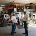 Two men talking to each other in a muffler shop.