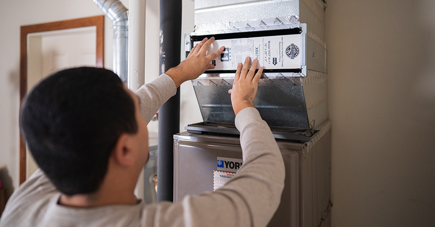 Image shows man replacing air filter in home